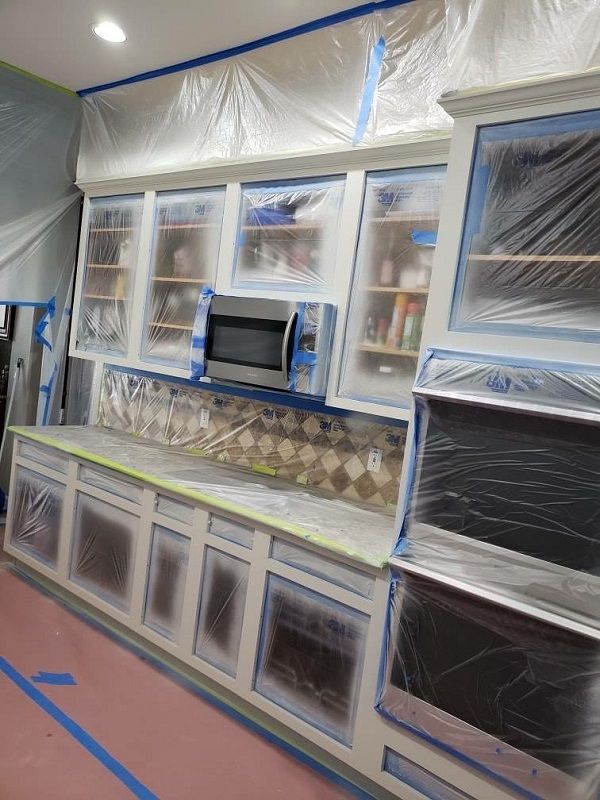 enlarged photo of in progress picture of kitchen cabinets and appliances covered in plastic with tape